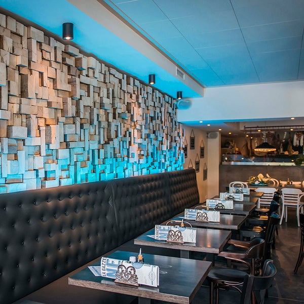 Innenaufnahme eines Restaurants mit Holzwand, Sitzbank und Tischen