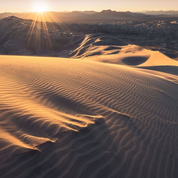 Sanddünen mit Sonnenaufgang im Hintergrund