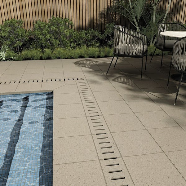 Moderne Poolumrandung mit quadratischen Fliesen und Entwässerungsrinne auf einer Terrasse mit Sitzbereich und Sichtschutzzaun.