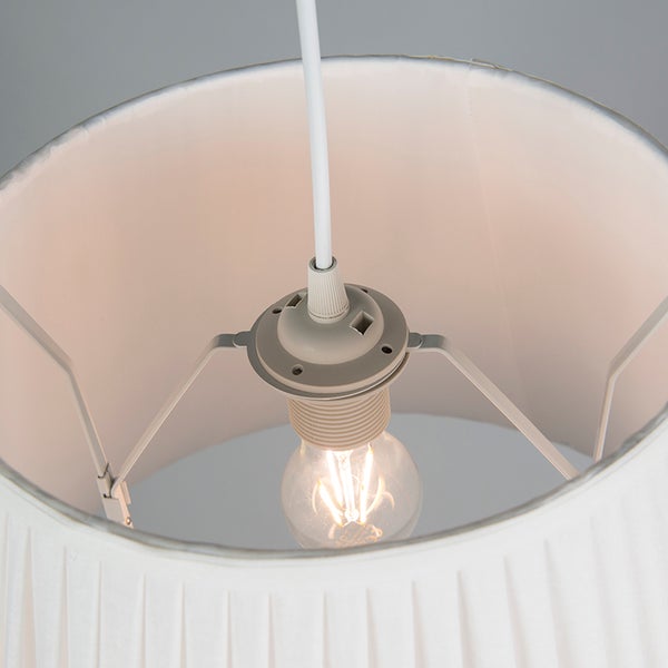 Innenansicht eines weißen plissierten Stofflampenschirms mit einem leuchtenden Filament-Leuchtmittel in einer Fassung.