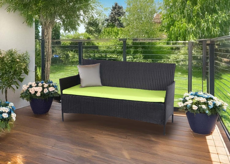 Moderne 2-Sitzer Gartenbank aus Polyrattan auf einer Holzterrasse mit hellgrüner Sitzauflage und Zierkissen vor einem Garten.