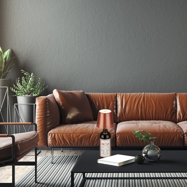 Moderne Wohnzimmereinrichtung mit braunem Ledersofa, schwarzem Couchtisch und einer Tischleuchte in Form einer Weinflasche.