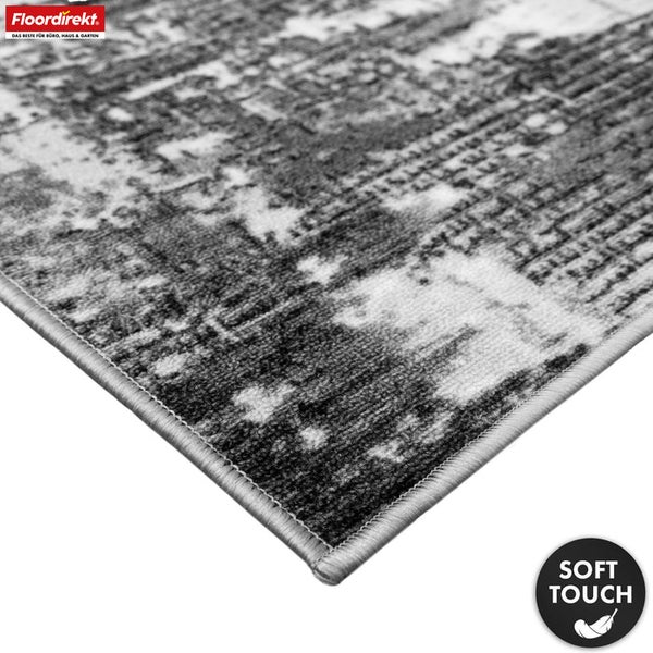 Detailansicht eines grauen Teppichs mit abstraktem Muster und Siegel für weiche Haptik