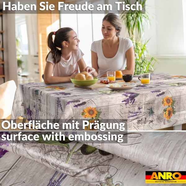 ANRO Deutsche Manufaktur Logo. Wachstuch-Tischdecke mit Sonnenblumen- und Lavendelmuster, geprägte Oberfläche, Frau und Kind am Tisch.