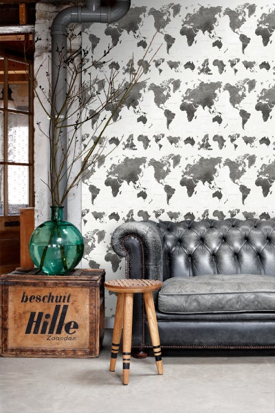 Wohnzimmer mit Weltkarten Tapete, Ledersofa, Holzhocker und dekorativer Holzkiste