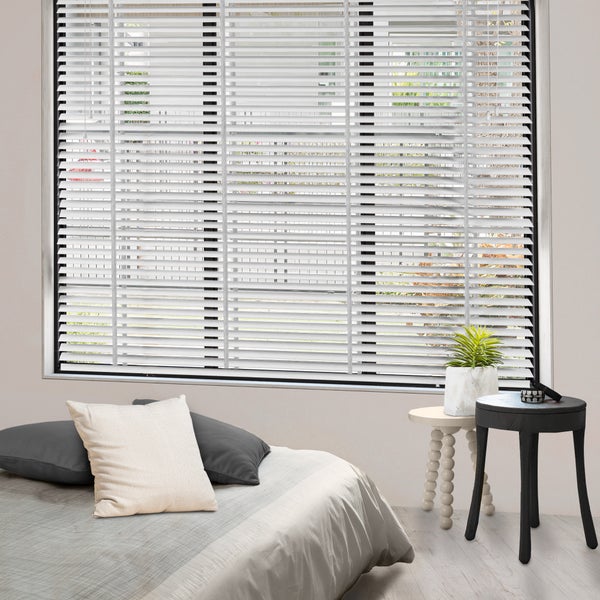 Innenaufnahme eines Schlafzimmers mit Bett, Beistelltischen und Jalousien am Fenster