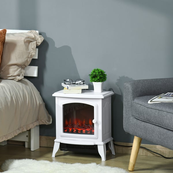 Elektrischer Kamin mit Flammeneffekt als Beistelltisch in einem Schlafzimmer mit Bett, Sessel und Dekoration auf der Tischplatte.