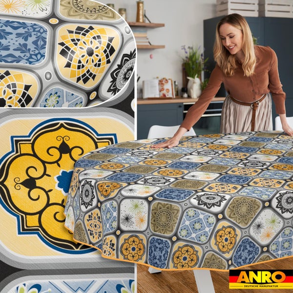 Frau breitet eine abwaschbare Wachstuch-Tischdecke mit Mosaik-Muster auf einem runden Tisch in einer hellen Küche aus. ANRO Logo.