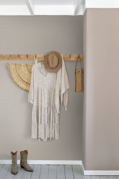 Helle Raumszene mit Holzgarderobe, Kleid, Hut und Stiefeln für eine gemütliche Atmosphäre.