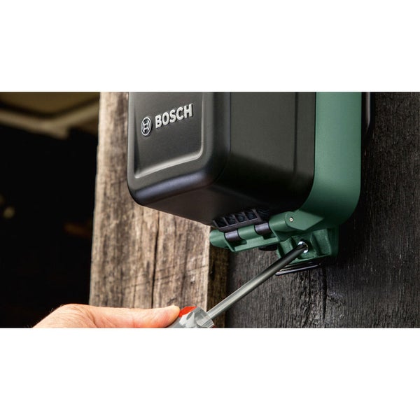 Installation einer Bosch Außensteckdose mit einem Schraubendreher an einem Holzzaun.