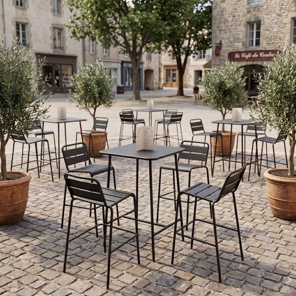 Moderne dunkelgraue Bistrotische und Barhocker aus Metall auf einem gepflasterten Platz mit Olivenbäumen in Tontöpfen.