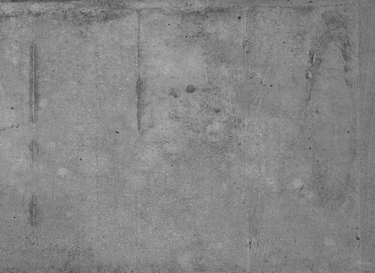 Strukturierte graue Betonoberfläche mit feinen Poren und Kratzern.