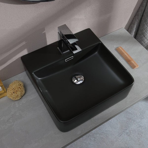 Quadratisches Aufsatzwaschbecken in Schwarz mit verchromter Armatur auf einer grauen Steinplatte im Badezimmer.