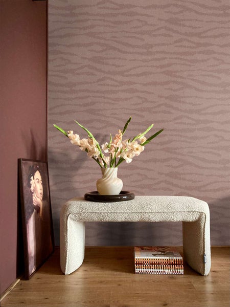 Wohnraum mit gemusterter Vliestapete, strukturierter Sitzbank aus Boucle Stoff, Blumenvasenarrangement und Wandbild auf Holzboden.