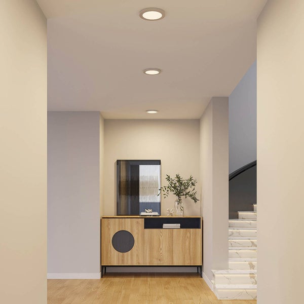 Moderner Flur mit drei runden LED Einbaustrahlern in der Decke, einem Sideboard aus Holz und einer beleuchteten Treppe.