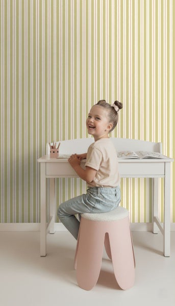Mädchen am Schreibtisch mit gestreifter Tapete im Kinderzimmer