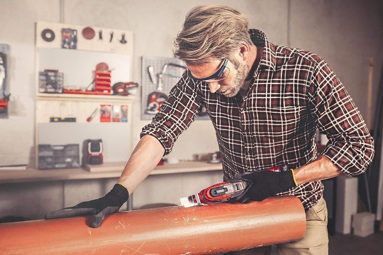 Handwerker arbeitet in einer Werkstatt mit einem oszillierenden Multifunktionswerkzeug an einem Kunststoffrohr.