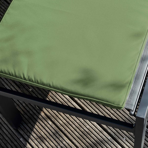 Grünes Sitzkissen auf einem schwarzen Gartenstuhlgestell auf einer Holzterrasse.