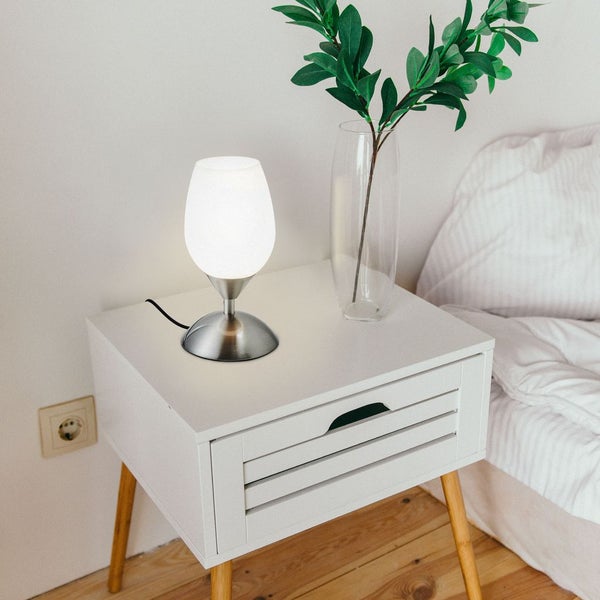 Nachttisch mit Lampe und Vase auf einem hellen Untergrund