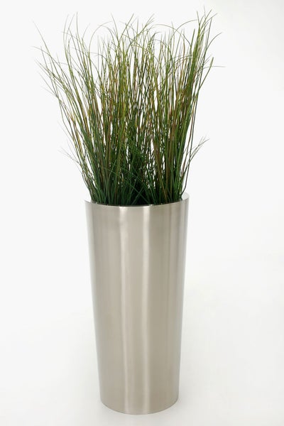 Künstliches Gras in einem hohen, zylindrischen Pflanzgefäß mit Metalloberfläche.