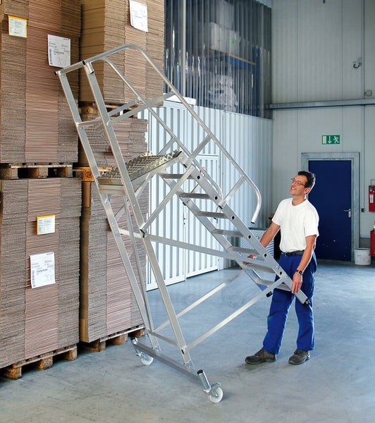 Mitarbeiter bewegt eine fahrbare Treppe aus Aluminium in einem Lager