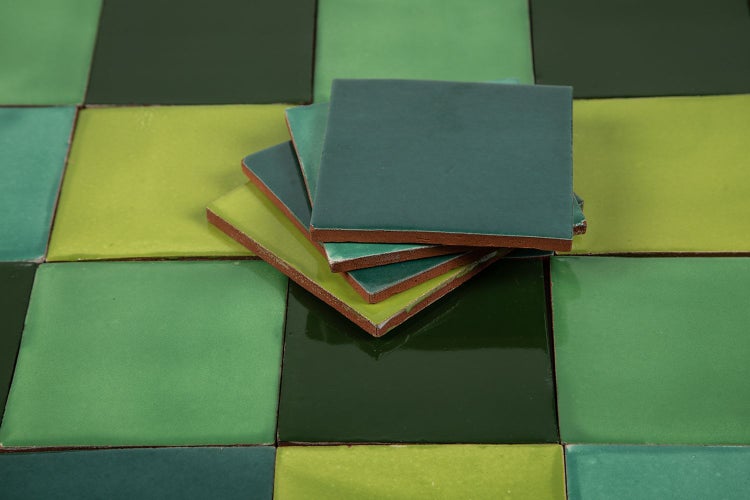 Quadratische Fliesen in verschiedenen Grüntönen liegen auf einem Schachbrettmuster.