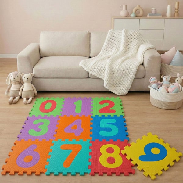 Bunte Puzzle-Spielmatte aus Schaumstoff mit Zahlen von 0 bis 9 in einem hellen Wohnzimmer vor einem Sofa.