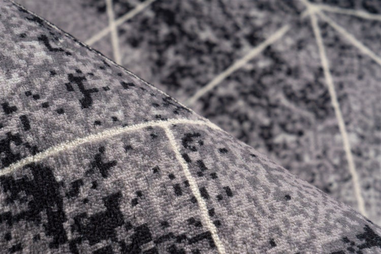 Strukturansicht eines Teppichs mit geometrischem Muster und gesprenkelter Textur.