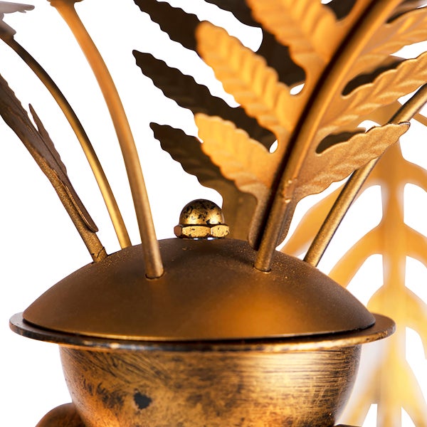 Detailaufnahme einer goldenen Dekolampe mit Pflanzenmotiven.