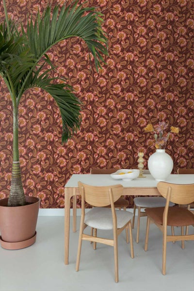 Vliestapete mit floralem Paisley-Muster in einem Esszimmer mit Holztisch, Stühlen und einer großen Zimmerpalme.