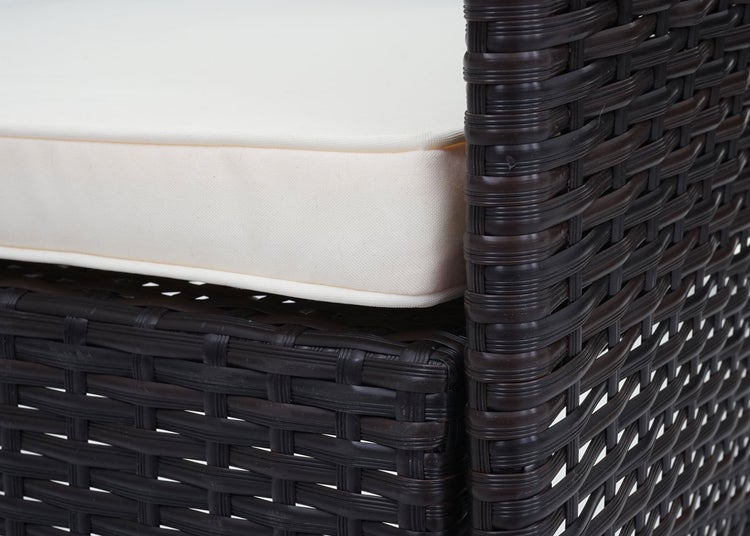 Nahaufnahme eines Gartenmöbelstücks aus Polyrattan-Geflecht mit dickem Sitzkissen.