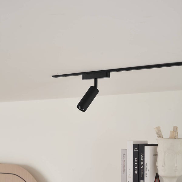 Schwarzer Strahler für Schienensystem an einer Decke in einem modern eingerichteten Raum.