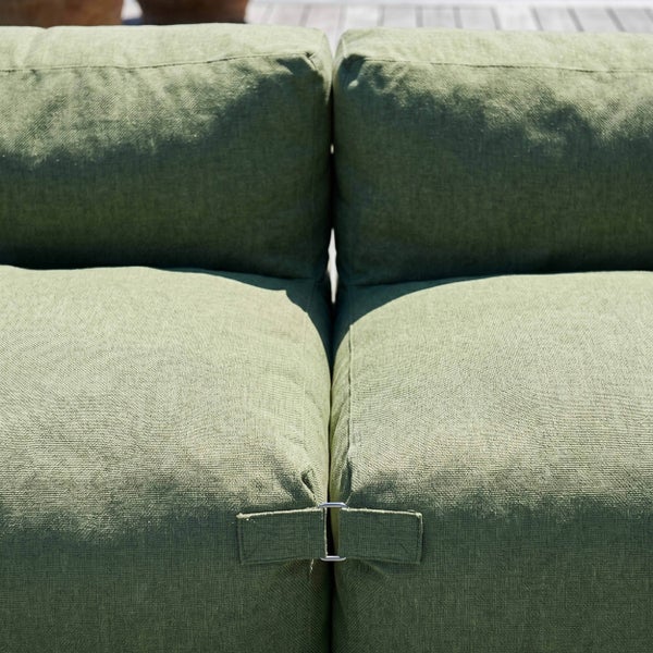 Detailaufnahme von zwei grünen Loungekissen für den Außenbereich, die mit einer Metallklammer verbunden sind.