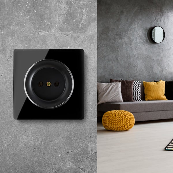Moderne Steckdose mit quadratischer Front in Wohnzimmer mit grauer Wand, Sofa und gelben Kissen.