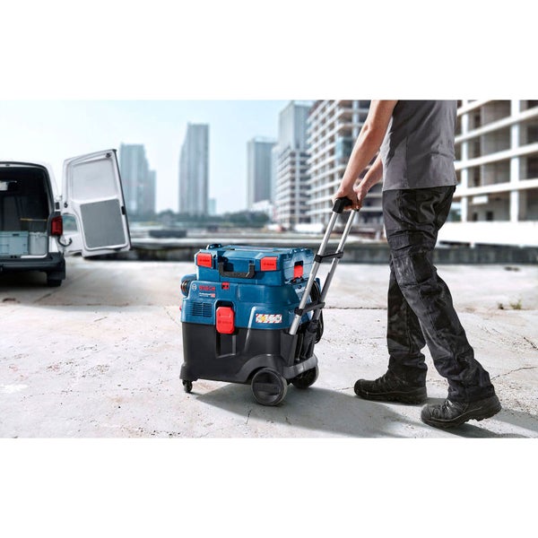 Handwerker transportiert Bosch Industriesauger auf einer Baustelle mit einem Rollwagen