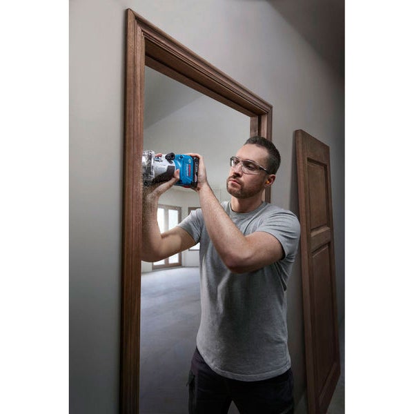 Ein Mann verwendet eine Oberfräse an einem Türrahmen, um diesen zu bearbeiten.