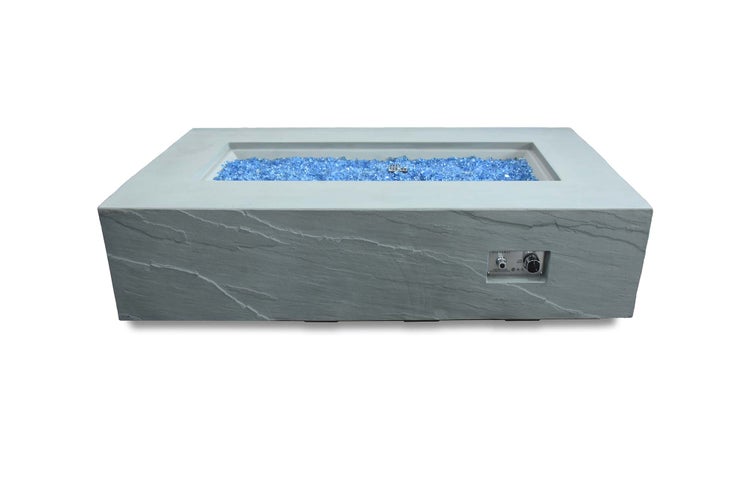 Rechteckiger Feuertisch aus Faserbeton mit integriertem Gasbrenner, Bedienknopf und blauen Glassteinen.