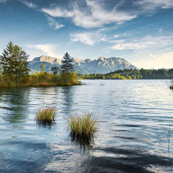 Landschaft mit See, Bäumen und Bergen