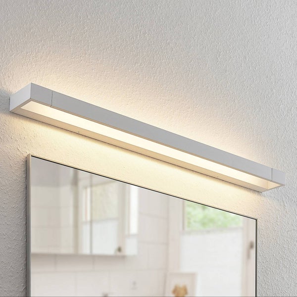 Moderne, längliche LED-Spiegelleuchte aus Metall über einem Badezimmerspiegel, warmweißes Licht strahlt nach oben und unten.