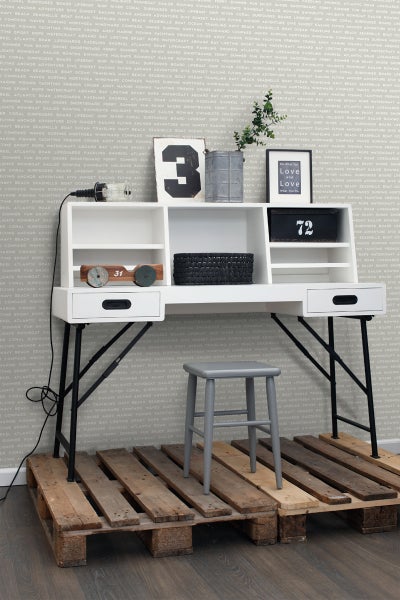 Schreibtisch mit Ablagefächern, Dekoration und grauem Hocker auf Holzpaletten
