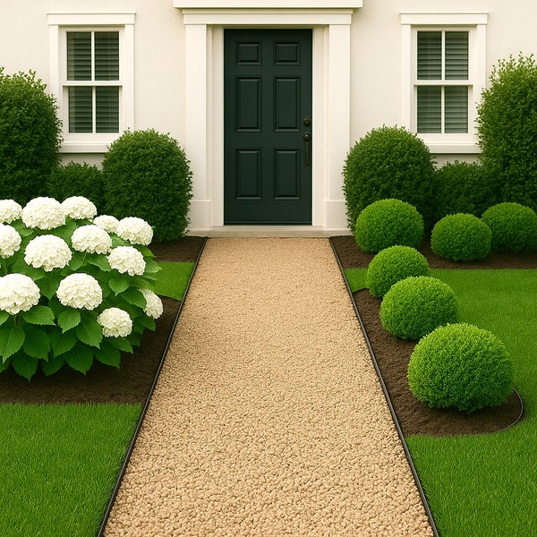 Gartenszene mit Kiesweg, Buchsbaumkugeln und Hortensien vor einem Haus