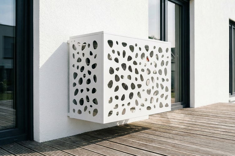 Verkleidung für Klimaanlage mit Lochmuster an einer Hauswand montiert