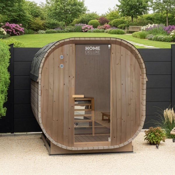 Fasssauna aus Holz von Home Deluxe im Garten vor einem Zaun stehend mit gläserner Eingangstür und hölzernem Innenbereich