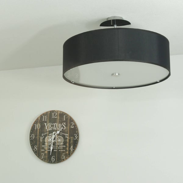 Eine runde Deckenleuchte mit Textilschirm und eine Wanduhr im Vintage Stil an einer weißen Wand.
