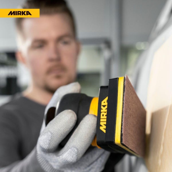 Handwerker schleift eine Holzoberfläche mit einem Mirka Handschleifblock.