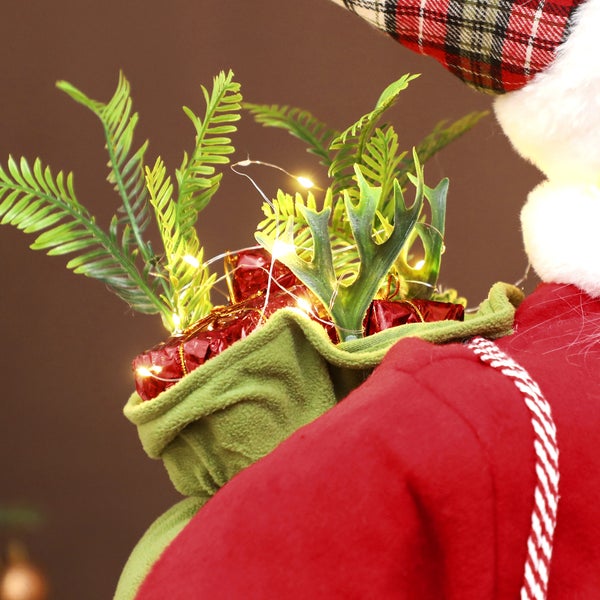 Detailansicht einer Weihnachtsmann-Figur mit Sack, Geschenken, Zweigen und einer Lichterkette.