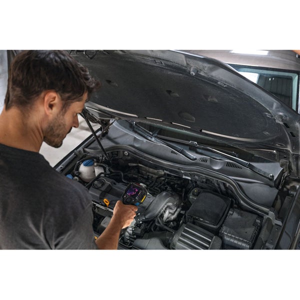 Ein Mann verwendet eine Wärmebildkamera zur Untersuchung eines Automotors.