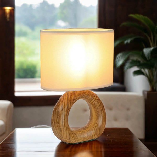 Tischleuchte mit Stoffschirm und Holzfuß auf einem Tisch