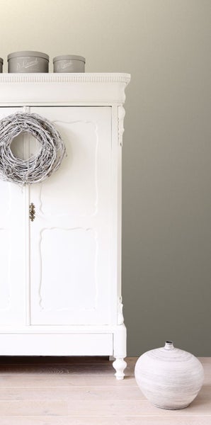 Dekoratives Arrangement mit einem weißen Kleiderschrank, einem Kranz und einer Vase