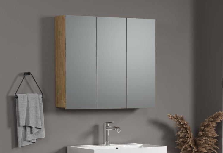 Spiegelschrank mit drei Spiegeltüren und Holzoptik Korpus über einem Waschbecken in modernem Badezimmer Ambiente.